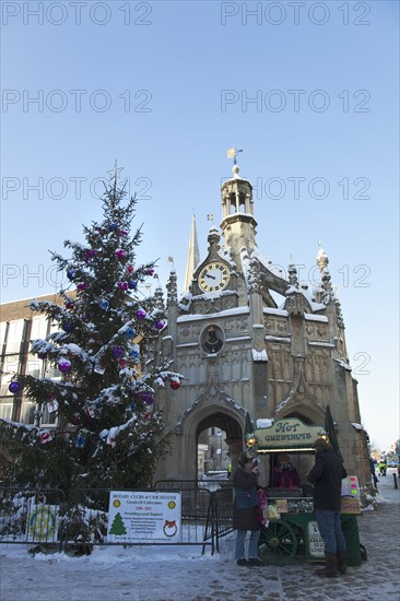 England, West Sussex, Chichester, The Cross and Christmas tree in snow with roast chestnut vendor.