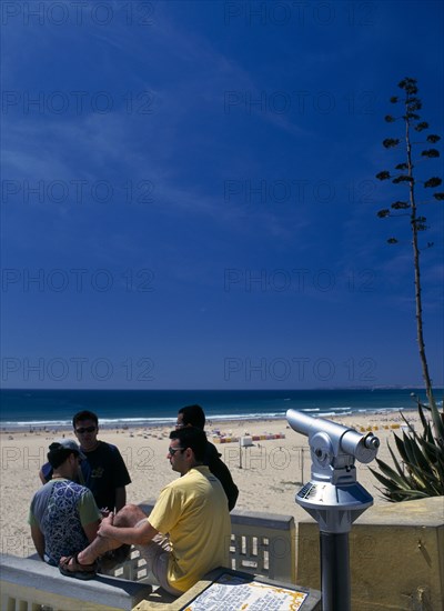 Portugal, Algarve, Praia da Rocha, View along beach with telescope and four young men in foreground