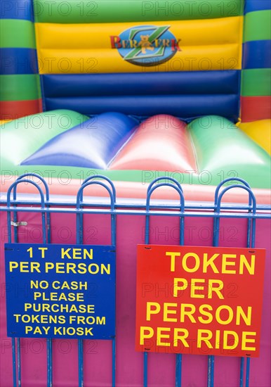 England, West Sussex, Bognor Regis, Empty colourful bouncy castle with signs on the Esplanade beside the beach.