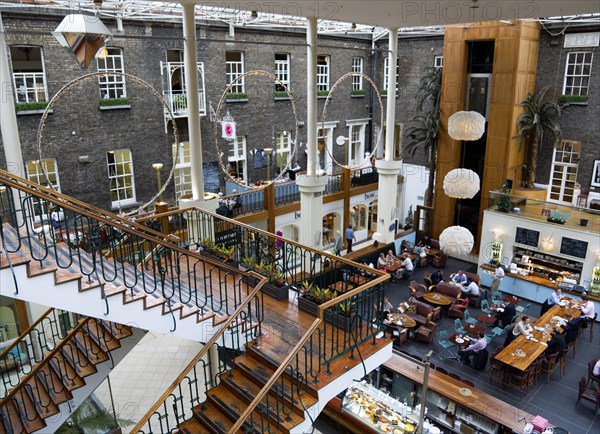 Ireland, County Dublin, Dublin City, Powerscourt Centre restaurants with people at tables beside shops in the enclosed old Georgian townhouse courtyard.