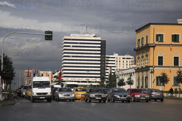 Albania, Tirane, Tirana, Traffic waiting at lights in Skanderbeg Square in front of the Tirana International Hotel.