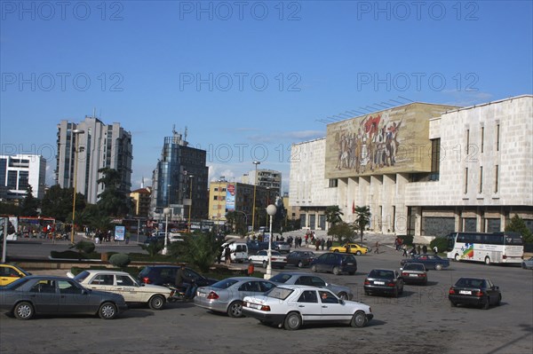 Albania, Tirane, Tirana, Traffic in Skanderbeg Square passing exterior facade of the National History Museum to the right.