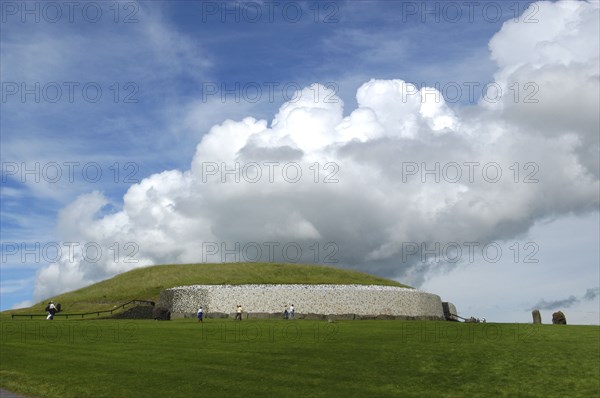 Ireland, Meath, Newgrange, Exterior view of the historical burial site that dates from 3200BC with visitors