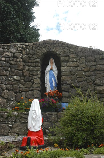 Ireland, General, Shrine in stone wall archway holding statue with flowers in front and statue of kneeling figure in the foreground