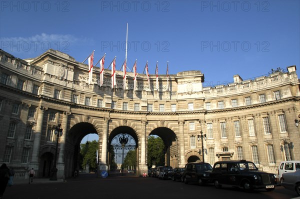 England, London, Admiralty Arch designed in 1911 by Aston Webb as part of a processional route to honour Queen Victoria with black cabs in the foreground