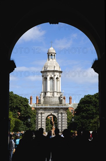 Ireland, County Dublin, Dublin City, Trinity College university with people walking through an arch at the entrance to Parliament Square leading towards the Campanile.