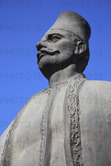 Albania, Tirane, Tirana, Part view of statue of standing male figure in traditional dress.