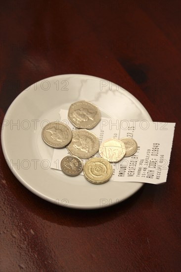 Food And Drink, Restaurant, Service, Saucer with credit card payment receipt and tip left for service after restaurant meal.