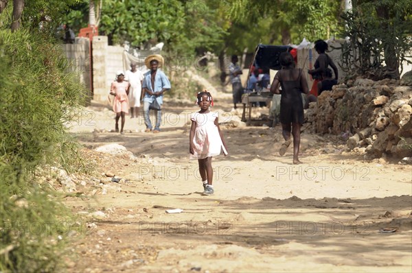 Haiti, La Gonave, Young girl walking along dirt track.