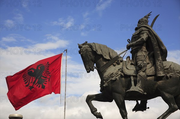 Albania, Tirane, Tirana, Equestrian statue of the national hero George Castriot Skanderbeg with national flag depicting double headed eagle against red background flying at side.