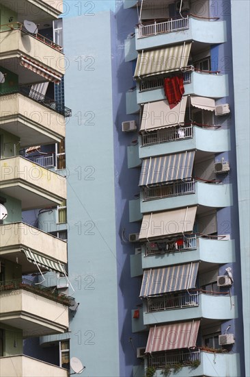 Albania, Tirane, Tirana, Detail of balconies and striped awnings on exterior facade of blue painted apartment block.