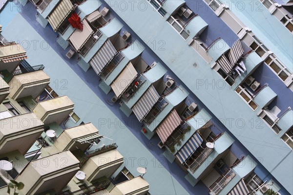 Albania, Tirane, Tirana, Angled view of balconies  striped awnings and satellite dishes on blue painted exterior facade of apartment block.