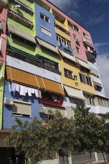 Albania, Tirane, Tirana, Part view of exterior facade of multi coloured apartment block with washing hanging from balconies beneath pulled out awnings.