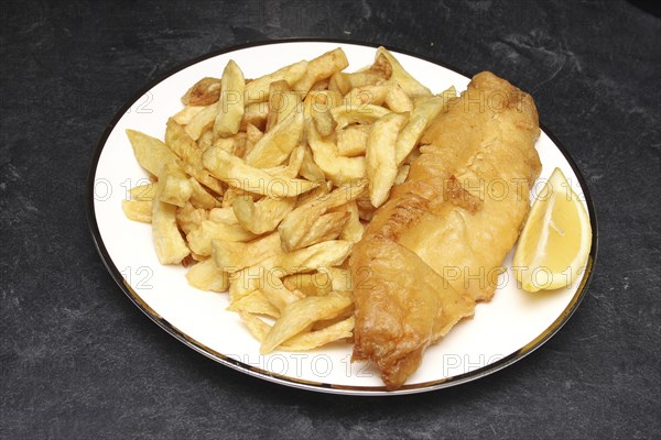 Food, Fast Food, Fish and Chips, Portion of deep fried chips and battered cod from Fish and Chip shop  on plate with lemon wedge at side of fish.