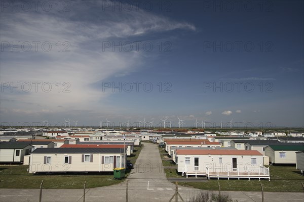 England, Kent, Romney Marshes, Old Romney  view over Camber holiday caravan park toward distant wind turbines.