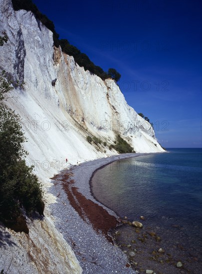 Denmark, Isle of Mon, Mons Klint, East facing chalk sea cliffs with flintstone beach.  Blue sky with high windswept clouds above.