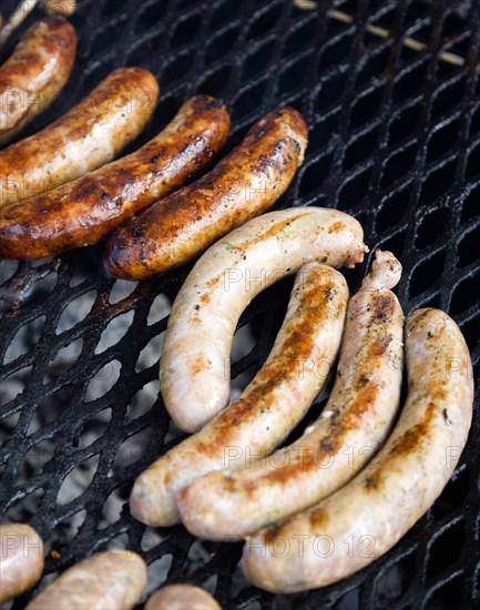 Food, Meat, Cooking, Sausages being cooked on a barbecue outdoor grill over hot coals.