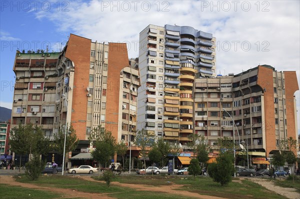Albania, Tirane, Tirana, Apartment blocks with shops below  overlooking road and area of grass and trees.