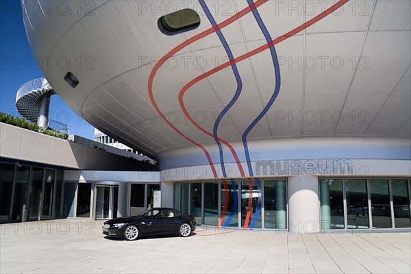 BMW Headquarters. The BMW Museum part view of orb shaped structure and entrance with car parked outside. Photo: Hugh Rooney