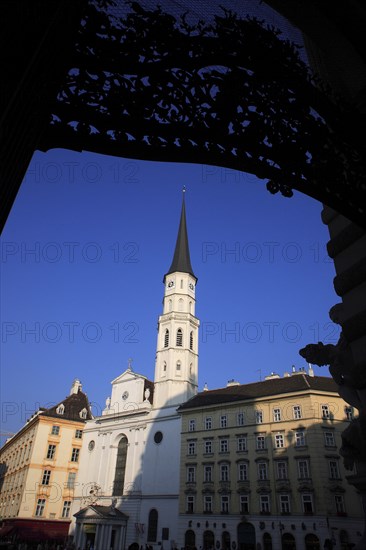 Angled view St Michaels Church exterior facade and spire against blue sky framed by decorative metal arch. Photo: Bennett Dean