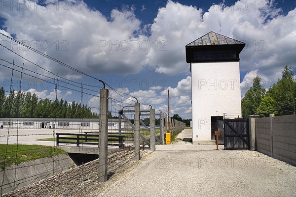 Dachau World War II Nazi Concentration Camp Memorial Site. Barbed wire fence with watch tower and reconstructed prisoner barracks. Photo : Hugh Rooney