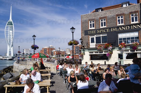 The 170 metre tall Spinnaker Tower and Historic Naval Dockyard seen from Spice Island in Old Portsmouth with The Spice Island Inn in the foreground with people seated at tables in Bath Square. Photo : Paul Seheult