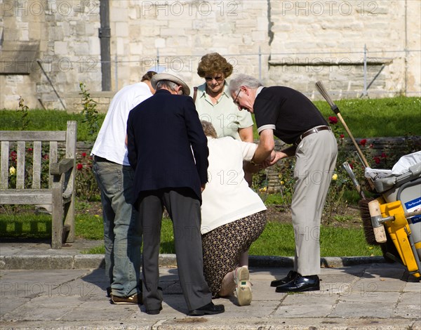 People helping an elderly lady to stand up after she has fallen on the pavement sidewalk outside the Anglican Cathedral in Old Portsmouth. Photo: Paul Seheult