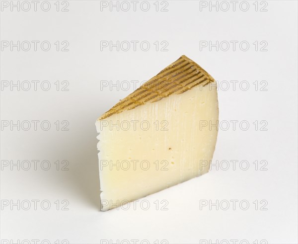 Slice of Spanish Manchego cheese made from pasteurised Manchega sheeps milk from the La Mancha region of Spain against a white background. Photo : Paul Seheult
