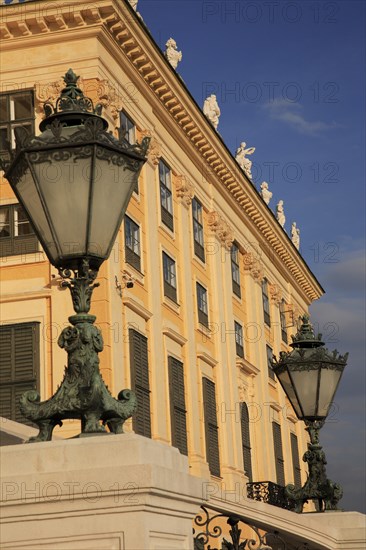 Schonnbrunn Palace. Part view of exterior facade with decorative metal lanterns on balcony in foreground. Photo: Bennett Dean