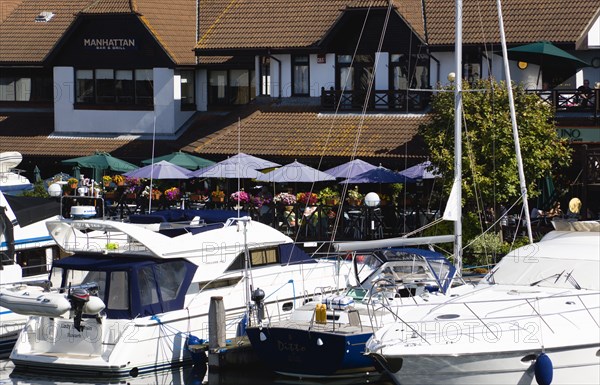 Port Solent Boats moored in the marina with people sitting at restaurant tables beyond. Photo : Paul Seheult
