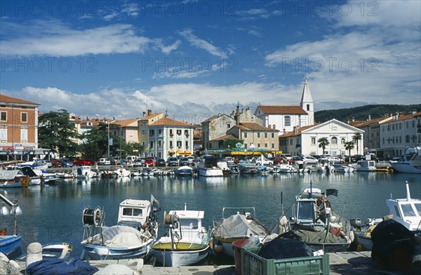 Port with fishing boats. Cars parked around the edge. Photo : Jonas Grau