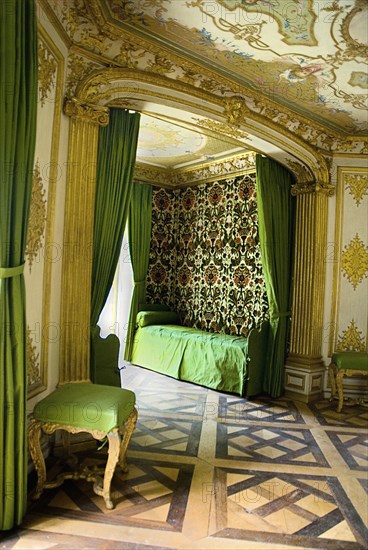 Nymphenburg Palace the Pagodenburg or bedroom. Green and gold decorated interior with day bed and chair. Photo : Hugh Rooney