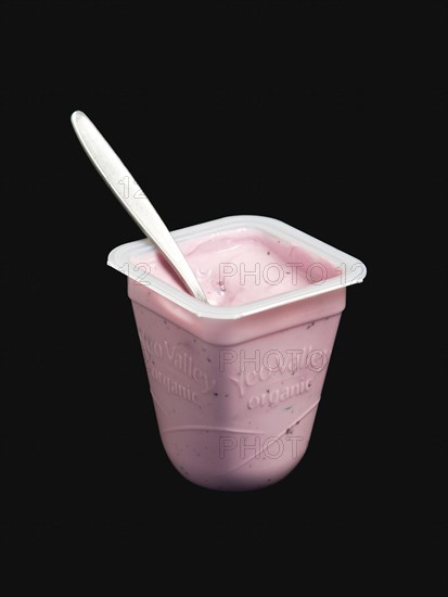 Yeo Valley probiotic blueberry fruit yogurt with spoon in pot against a black background. Photo : Paul Seheult