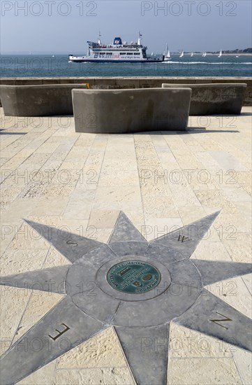 A plaque within a compass on the Millenium Walk commemorating its opening by Prince Phillip The Duke of Edinburgh with an Isle Of Wight ferry passing through the harbour entrance. Photo: Paul Seheult