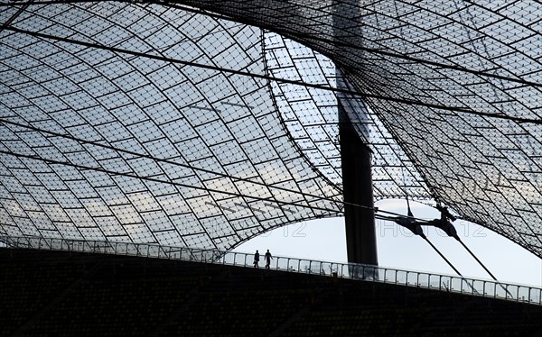 Olympic Stadium built as the main venue for the 1972 Summer Olympics. Pair of tourists silhouetted on balcony beneath large sweeping canopies of acrylic glass stabilised by steel cables meant to represent the Alps. Photo : Hugh Rooney
