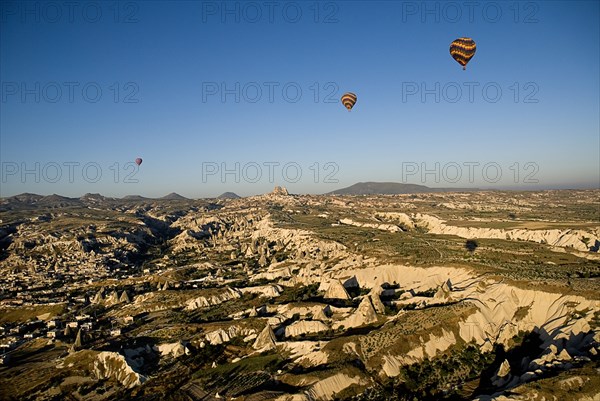 Hot air balloons in flight over landscape in early morning sunlight with Uchisar town in background and Goreme to the left.. Photo: Hugh Rooney