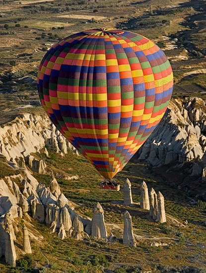 Brightly coloured hot air balloon in flight over rock peaks and pinnacles of Love Valley in early morning. Photo: Hugh Rooney