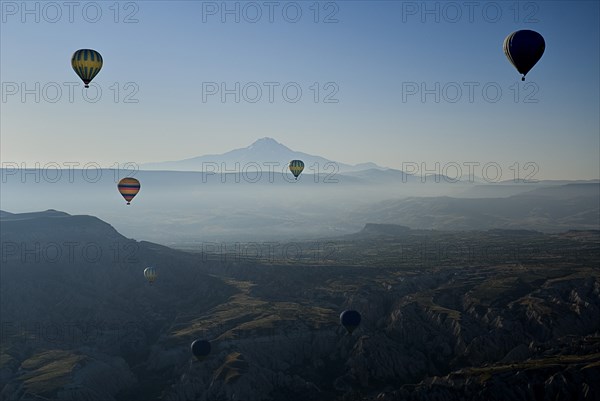 Early morning with hot air balloons in flight mist drifting across landscape and Mount Erciyes in the background. Photo : Hugh Rooney