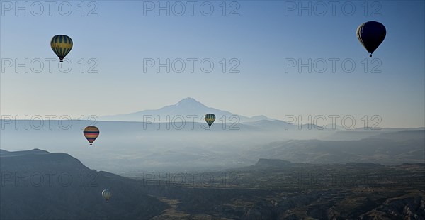 Early morning with hot air balloons in flight mist drifting across landscape and Mount Erciyes in the background. Photo : Hugh Rooney