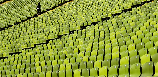 Olympic Stadium. Curved section of bright green seating in the stadium with standing figure at far end. Photo: Hugh Rooney