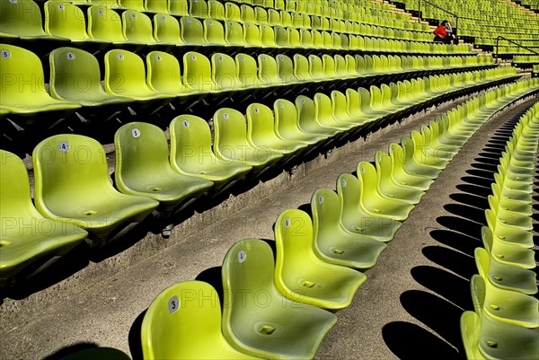 Olympic Stadium. Curved section of bright green seating in the stadium with couple seated at far end. Photo: Hugh Rooney