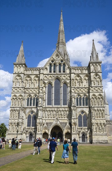 People on the grass of the Close in front of the West Front main entrance of the 13th Century Early English Gothic Cathedral Church of the Blessed Virgin Mary with the tallest spire in Britain. The statues conform to a carefully considered iconography bas. Photo : Paul Seheult