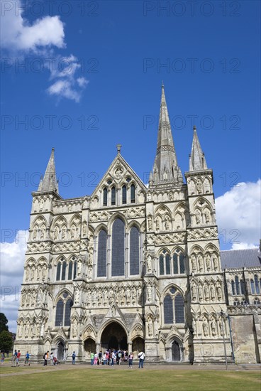 People on the grass of the Close in front of the West Front main entrance of the 13th Century Early English Gothic Cathedral Church of the Blessed Virgin Mary with the tallest spire in Britain. The statues conform to a carefully considered iconography bas. Photo : Paul Seheult