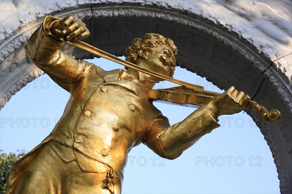 Angled part view of statue of Johann Strauss in the Stadt Park framed by stone arch. Photo: Bennett Dean