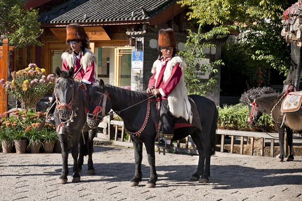 Naxi men on horseback wearing traditional costume including Red panda skin hats. Photo : Mel Longhurst