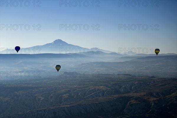 Early morning with hot air balloons in flight mist drifting across landscape and Mount Erciyes in the background. Photo : Hugh Rooney