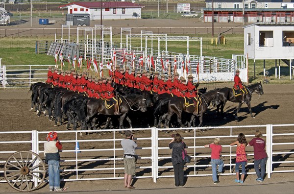 Canada, Alberta, Lethbridge, Royal Canadian Mounted Police Musical Ride 32 RCMP cavalry in full dress red serge uniform on horseback holding lances with red and white pennons saluting with an eyes right led by commanding officer with sword drawn Mounties put on riding displays across Canada and around the world. 
Photo : Trevor Page