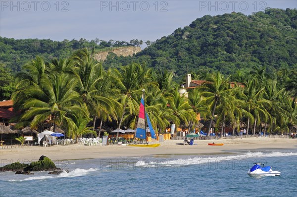 Mexico, Guerrero, Zihuatanejo, View across water towards Playa la Ropa sandy beach lined with lush green palm trees. 
Photo : Nick Bonetti