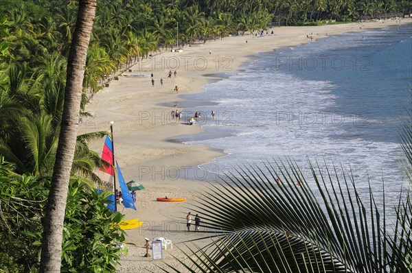 Mexico, Guerrero, Zihuatanejo, View along the shoreline of Playa la Ropa lined with palm trees. A colourful sailboat on sandy beach. 
Photo : Nick Bonetti