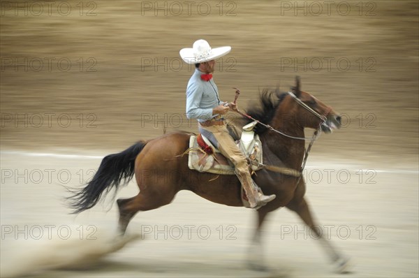 Mexico, Bajio, Zacatecas, Traditional horseman or Charro performing at Mexican rodeo. Single horse and rider in blur of movement. 
Photo : Nick Bonetti